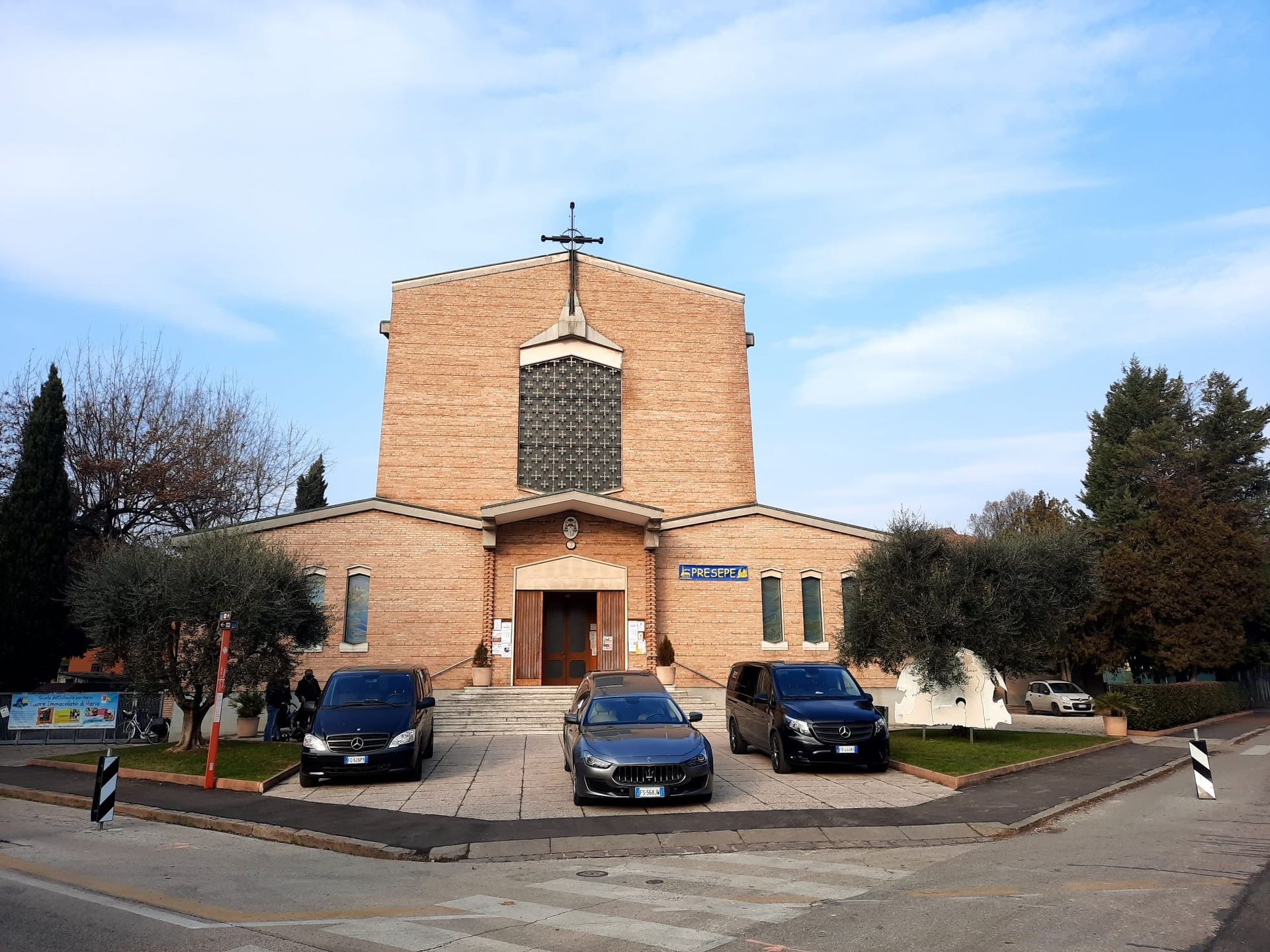 Tre auto funebri sono parcheggiate davanti a una chiesa.