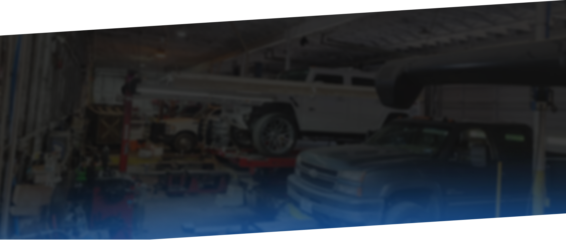 Cars inside a garage, one lifted up, other on the floor. Tools and equipment.