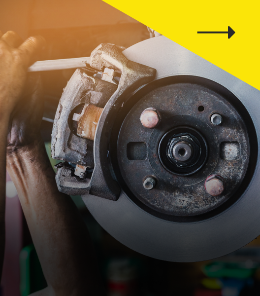 Mechanic working on a car brake rotor. Sunlight illuminates the scene.