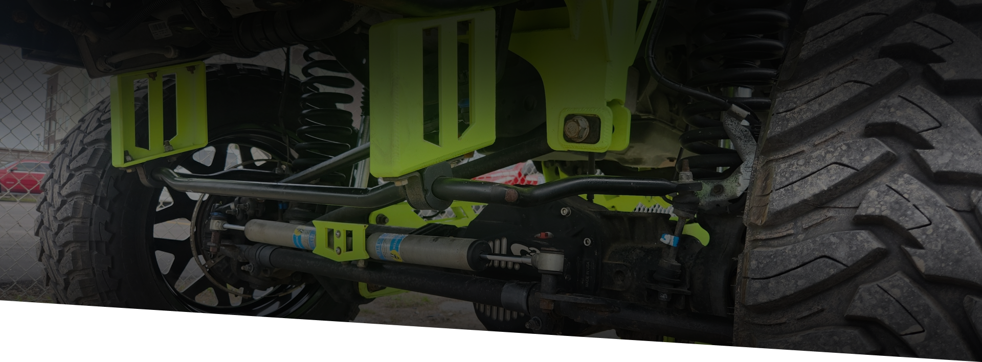 Close-up of a lifted truck suspension with large tires and yellow-green components.