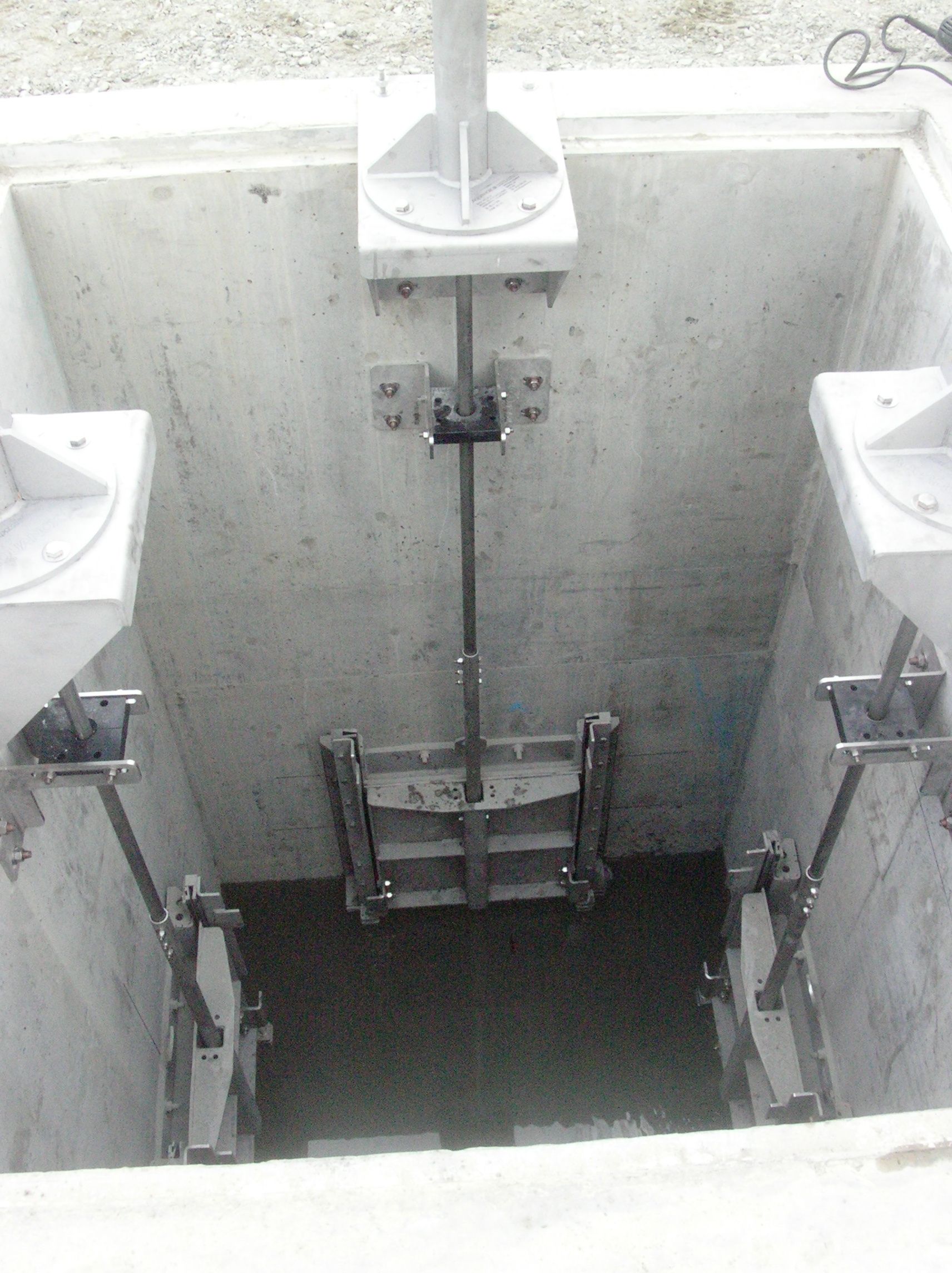 A black and white photo of a concrete wall with a mechanical device in it