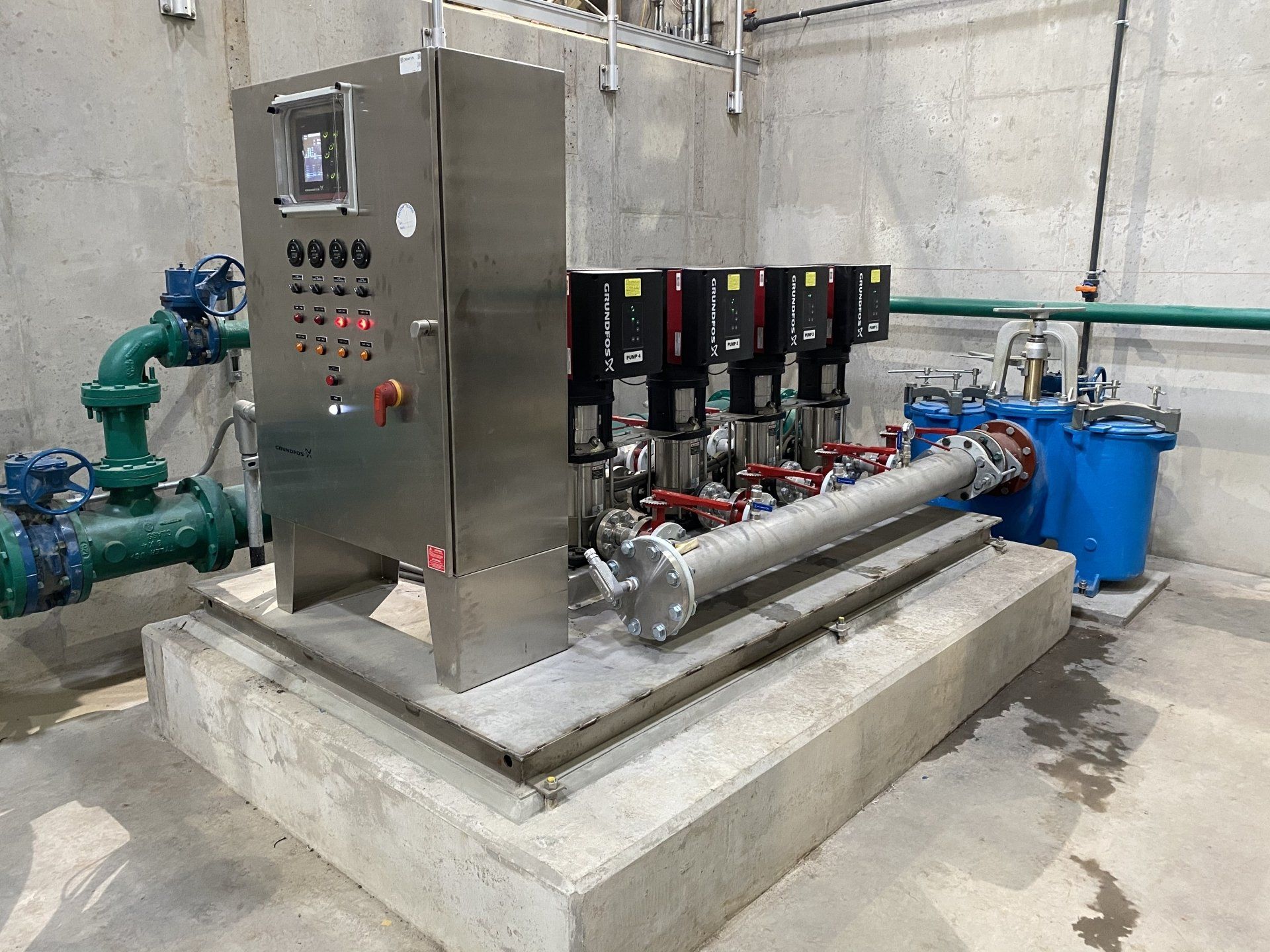 A stainless steel machine is sitting on top of a concrete platform in a room.