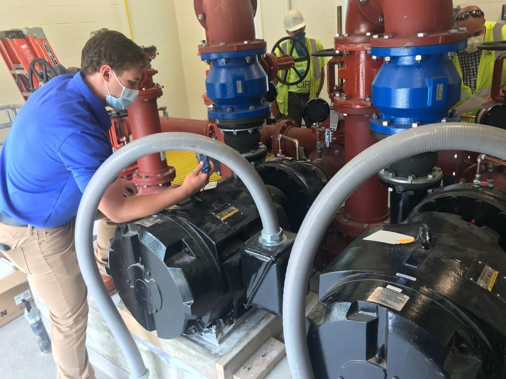 A man wearing a mask is working on a machine.