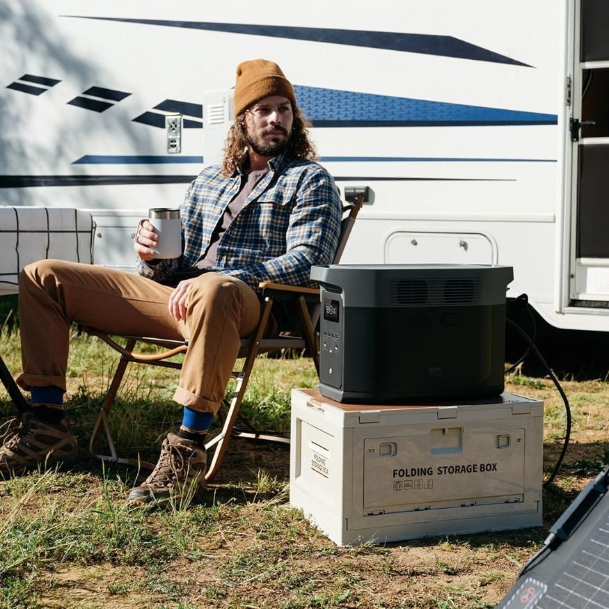 A Man is Sitting in a Chair in Front of a Trailer Holding a Cup of Coffee — Battery World Townsville In Garbutt, QLD