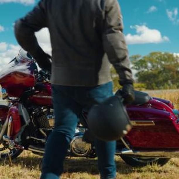 A Man is Standing Next to a Red Motorcycle Holding a Helmet — Battery World Townsville In Garbutt, QLD