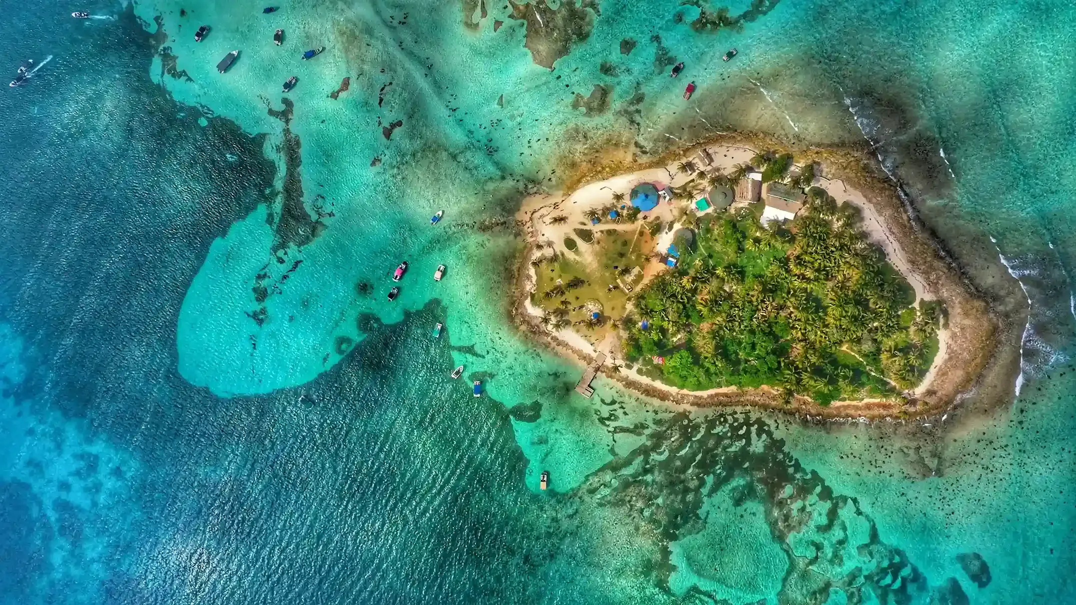 Vista aérea de islote rodeado de mar turquesa y pequeñas embarcaciones en San Andrés.