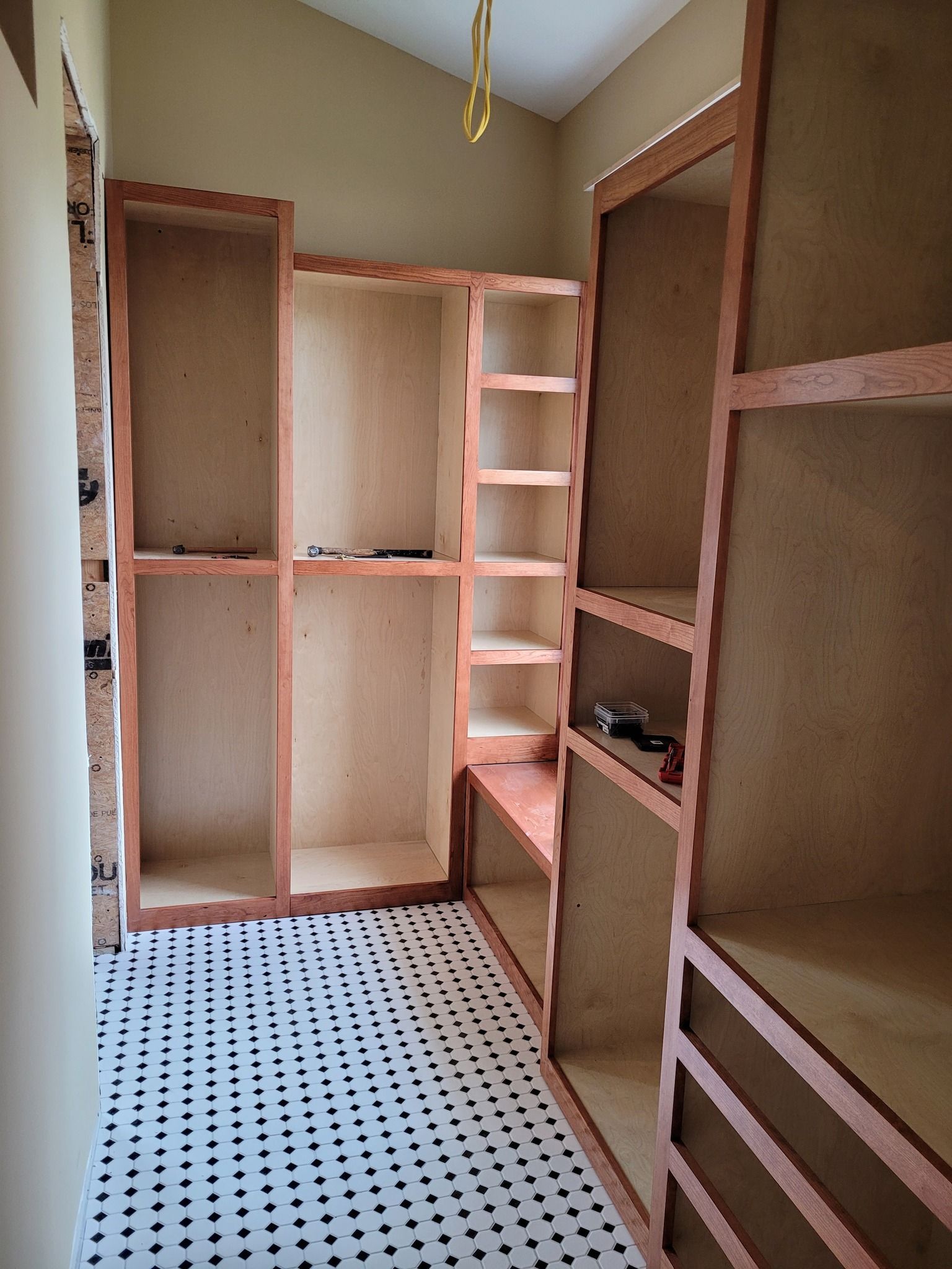A closet with wooden shelves and drawers is being built in a house.