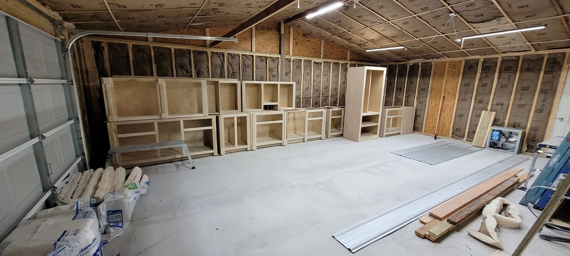 A garage is being remodeled with a lot of wooden cabinets and shelves.