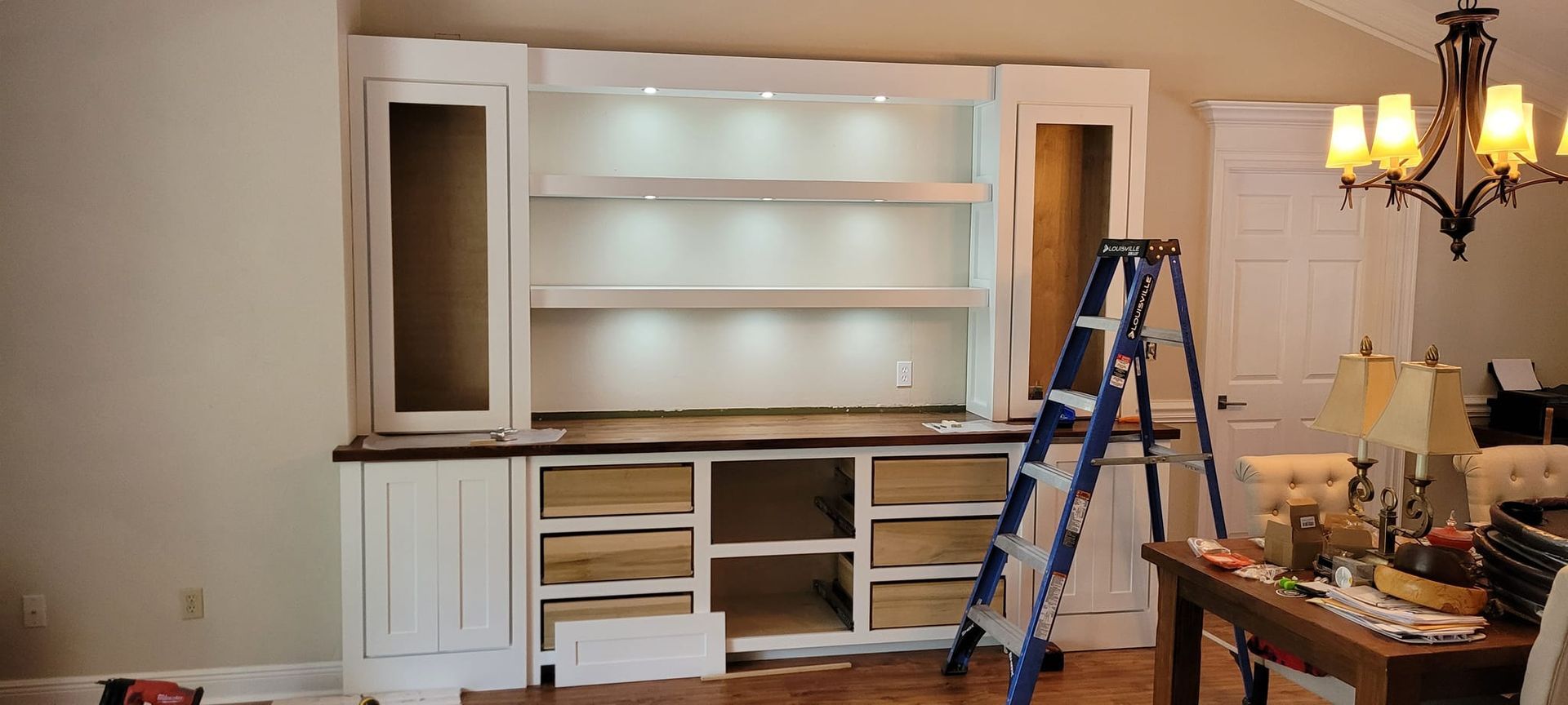 A ladder is sitting in front of a large cabinet in a living room.