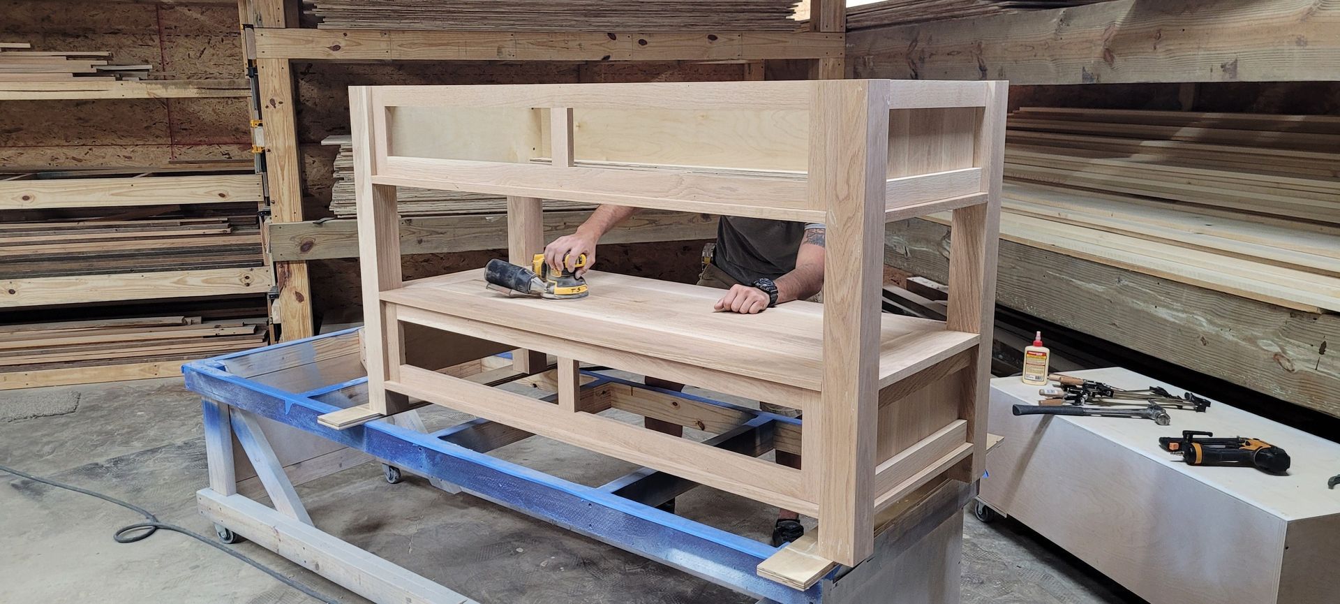 A man is working on a wooden table in a workshop.