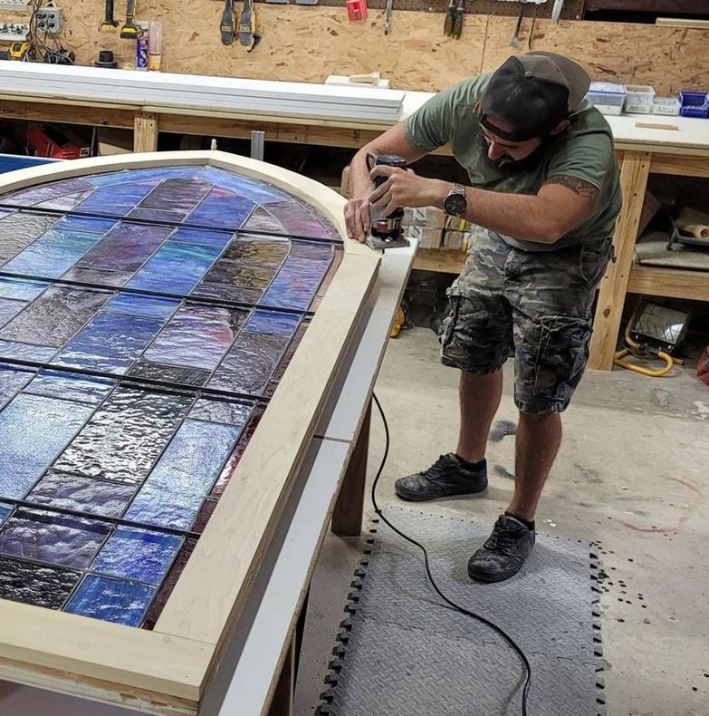 A man is working on a stained glass window