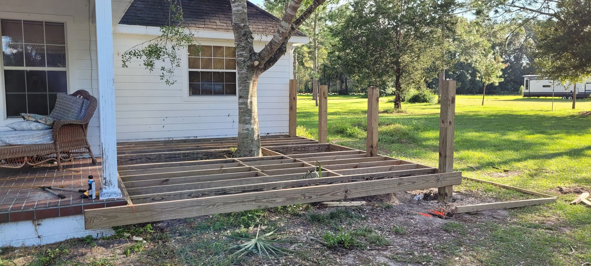 A wooden deck is being built in front of a white house.