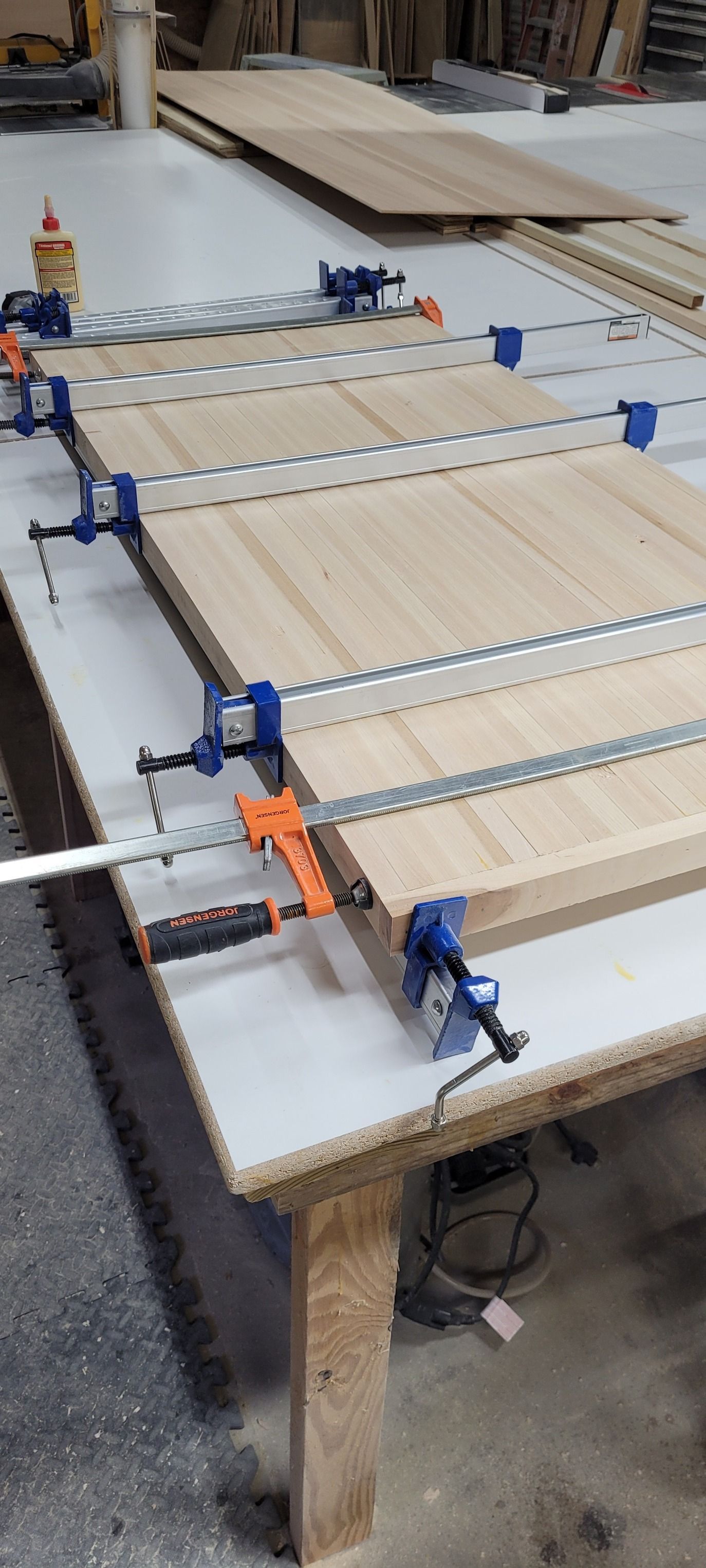 A wooden table with a lot of clamps on it.