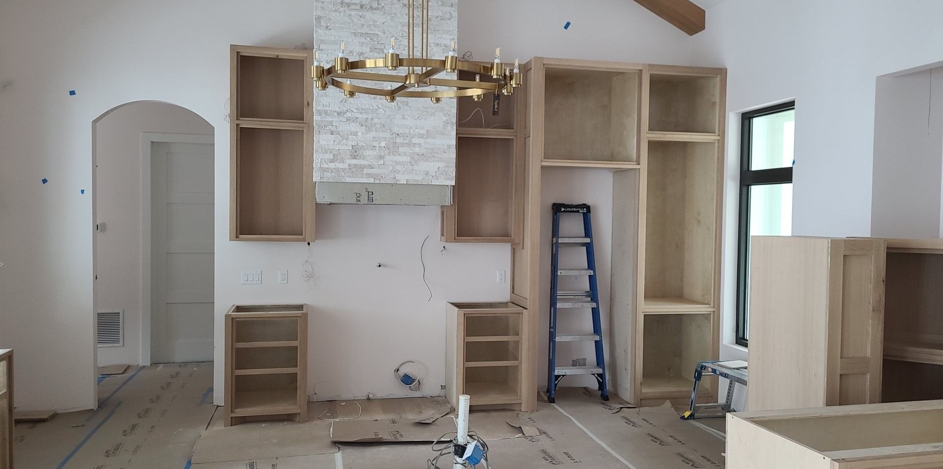 A kitchen under construction with wooden cabinets and a ladder.