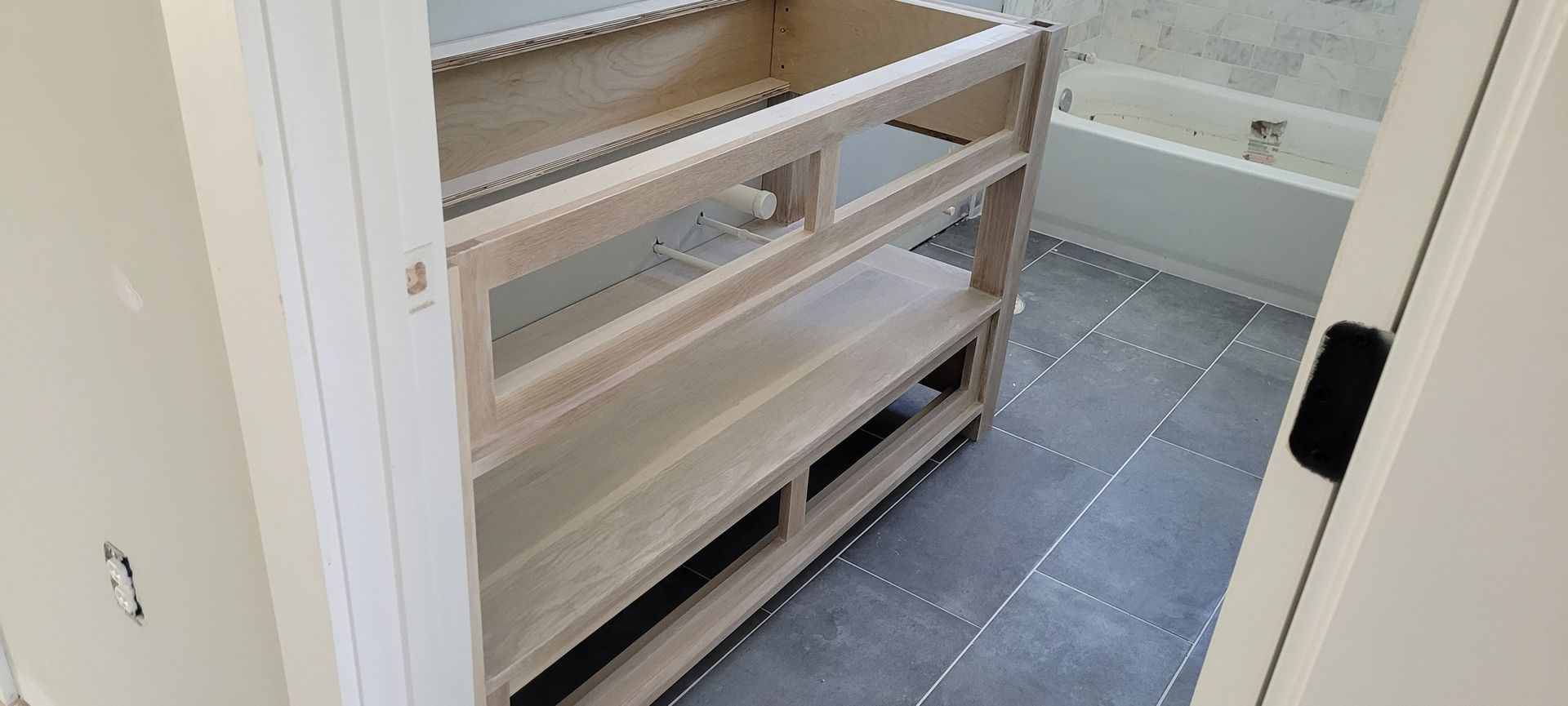 A bathroom vanity is being built in a bathroom next to a bathtub.