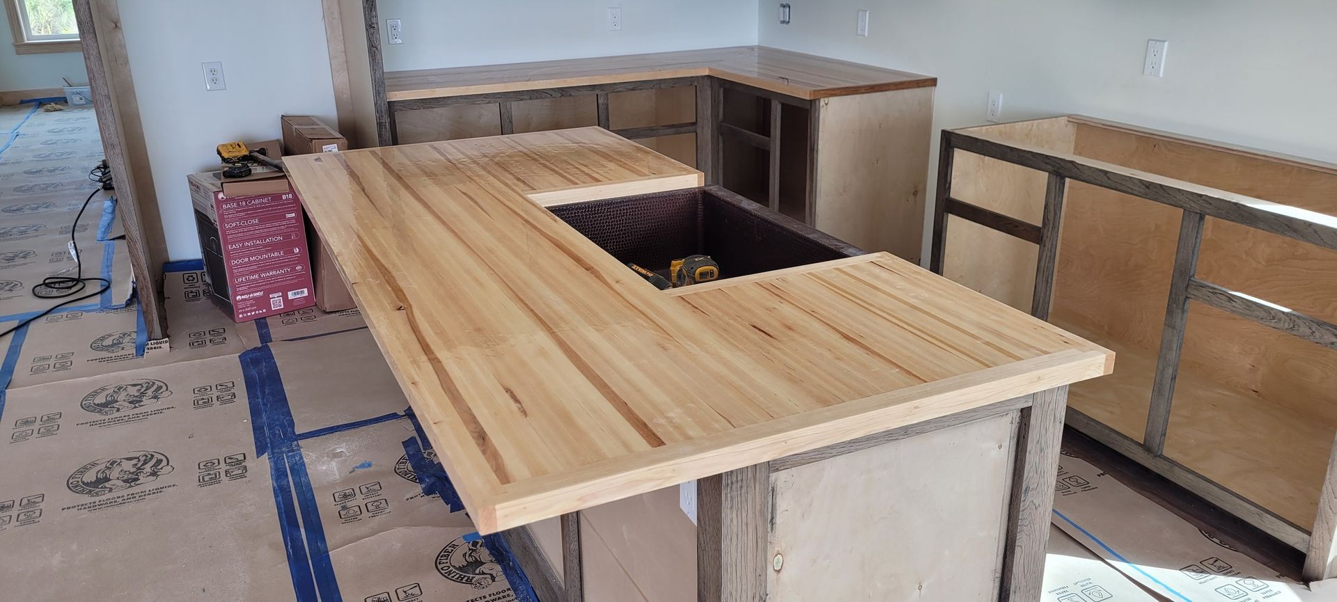 A kitchen under construction with a wooden counter top and a sink.