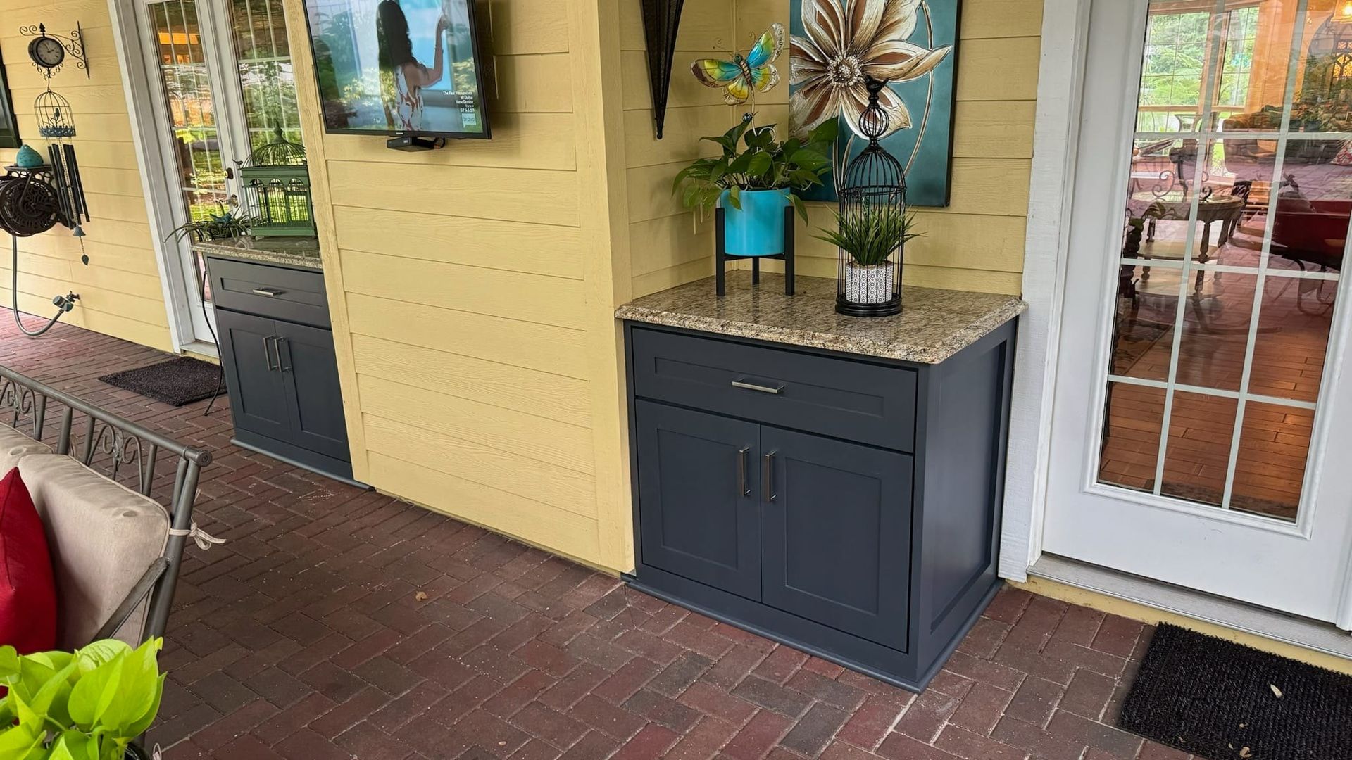 A patio with a gray cabinet and a flat screen tv on the wall.