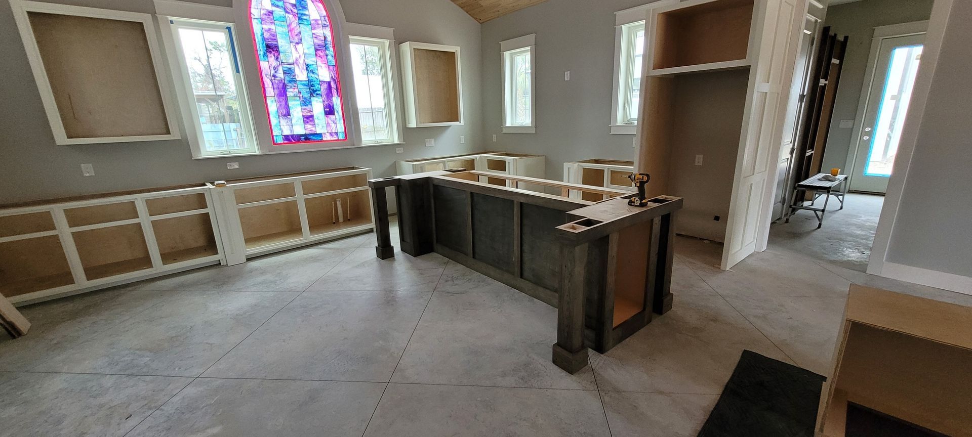 A kitchen is being built in a church with a stained glass window.
