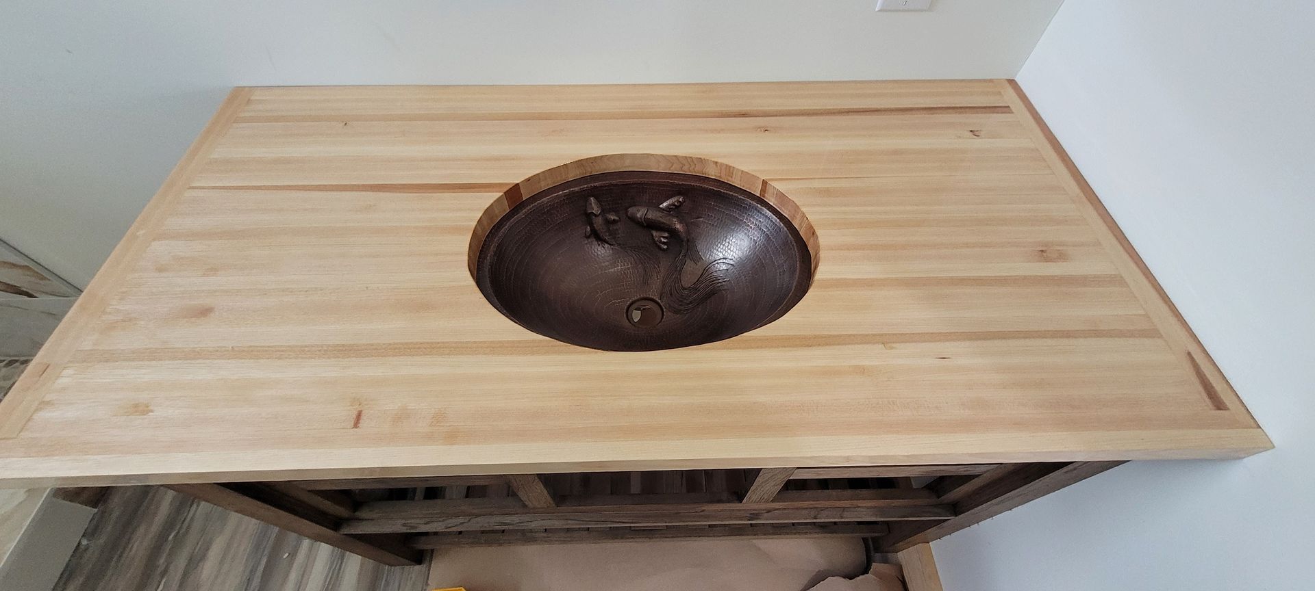 A wooden counter top with a sink in the middle of it.