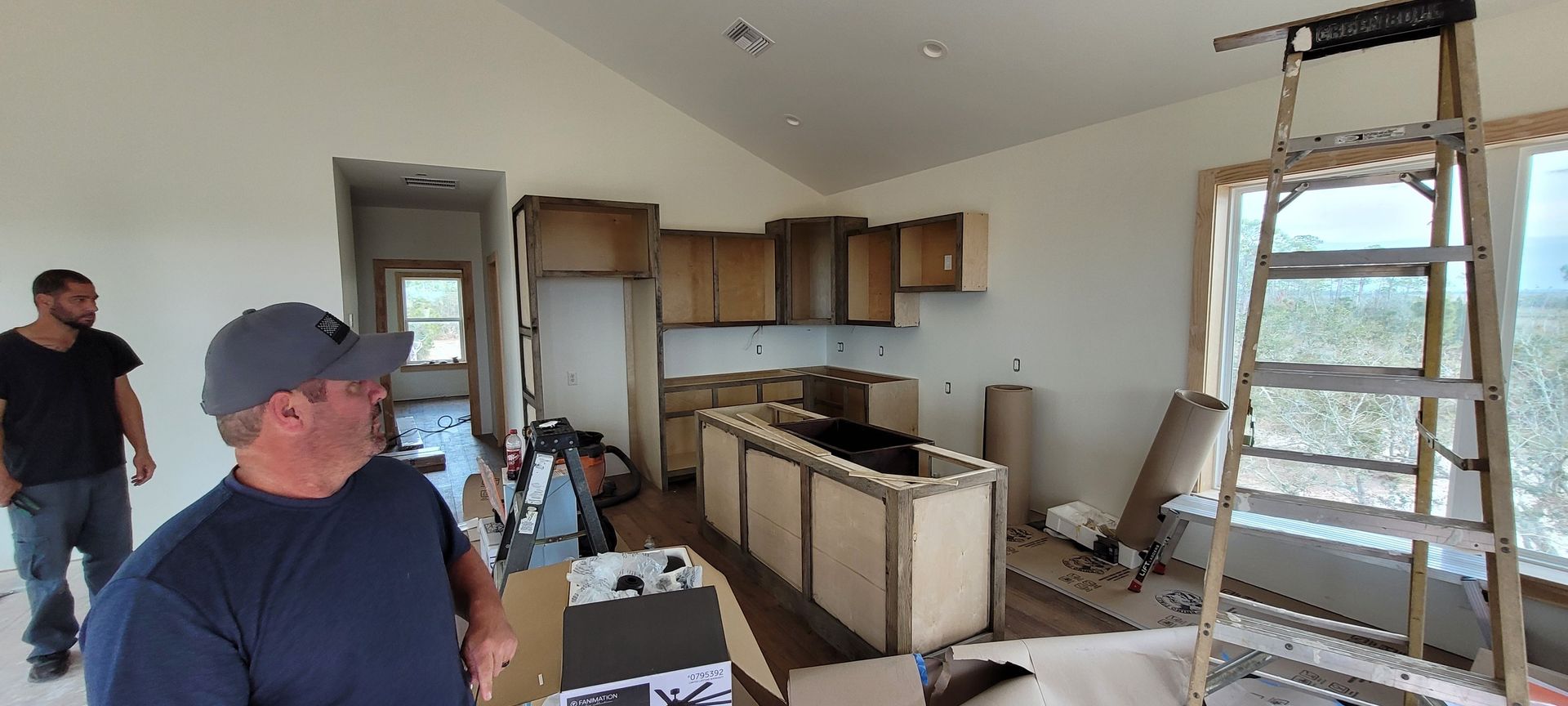 Two men are standing in a kitchen under construction.