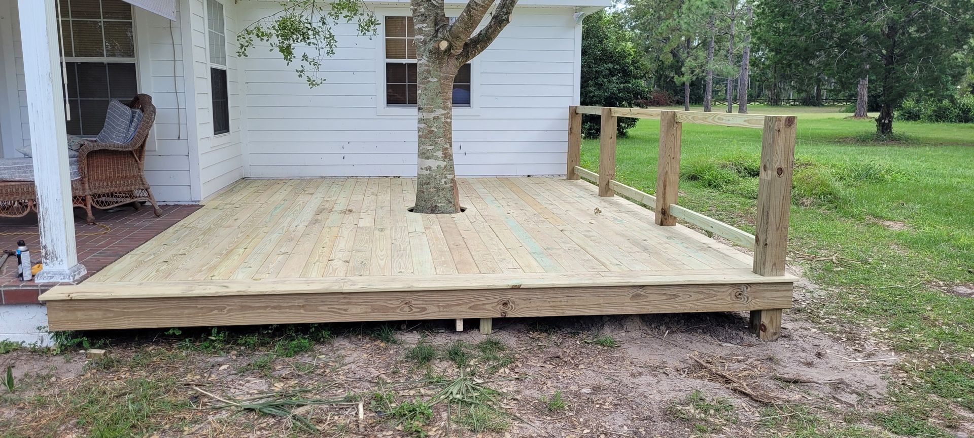 A wooden deck is sitting in front of a white house.