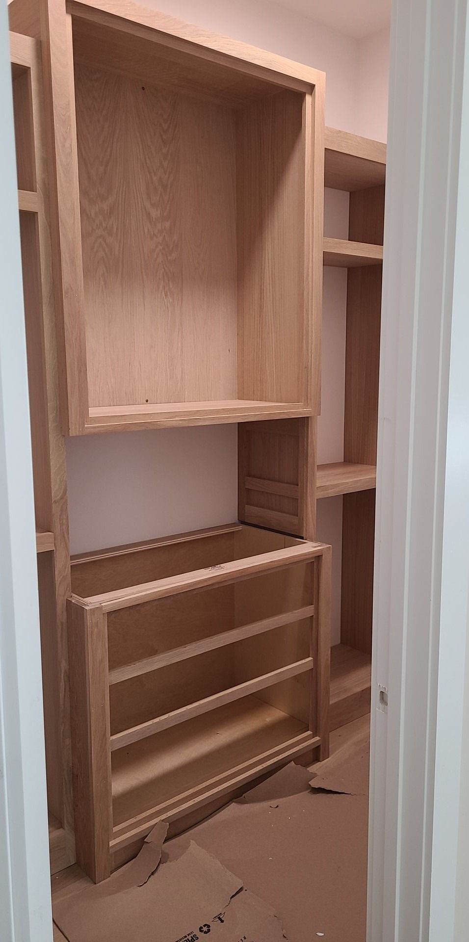 A closet with wooden shelves and drawers is being built in a house.