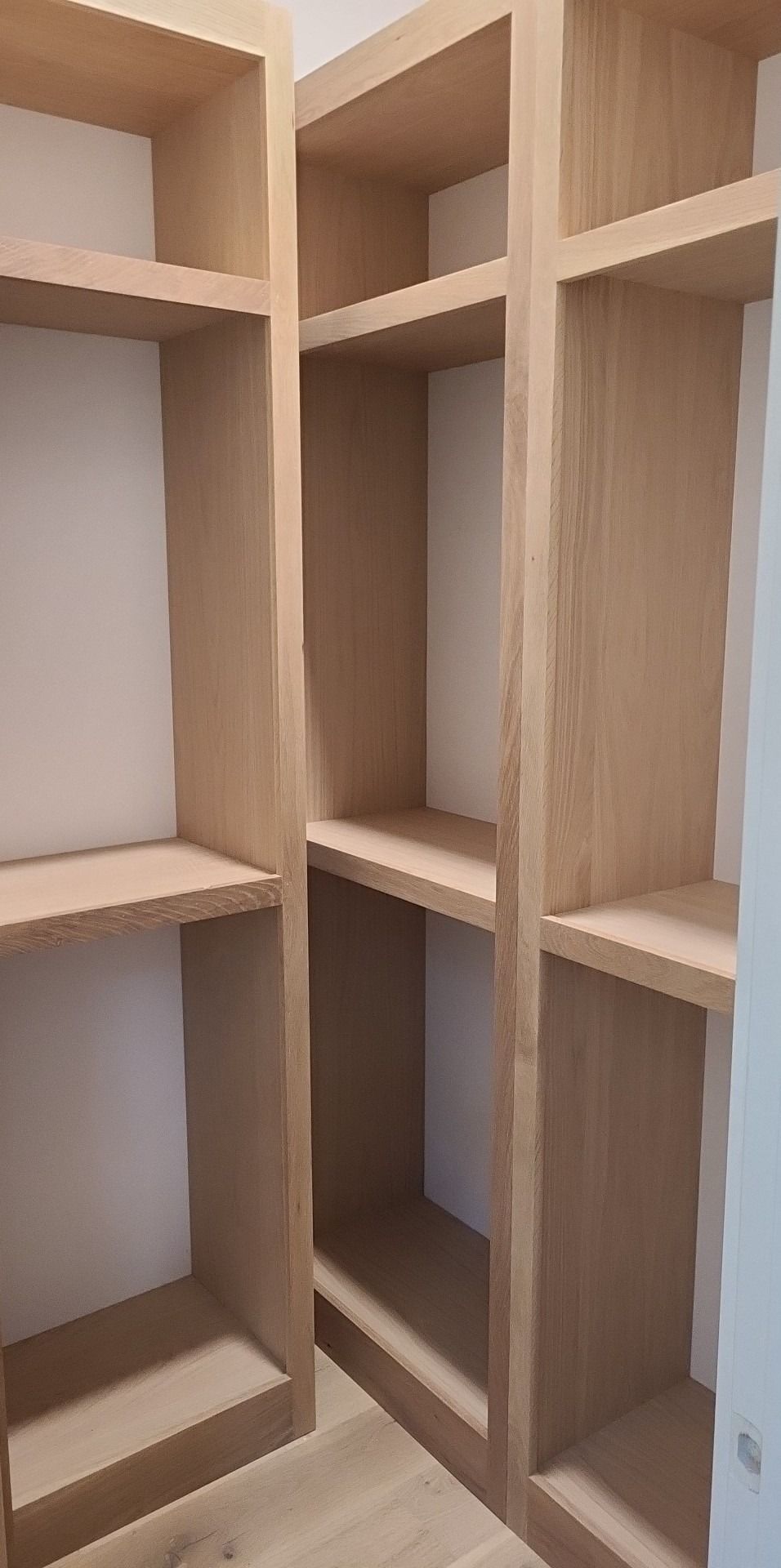 A walk in closet with wooden shelves and a door.