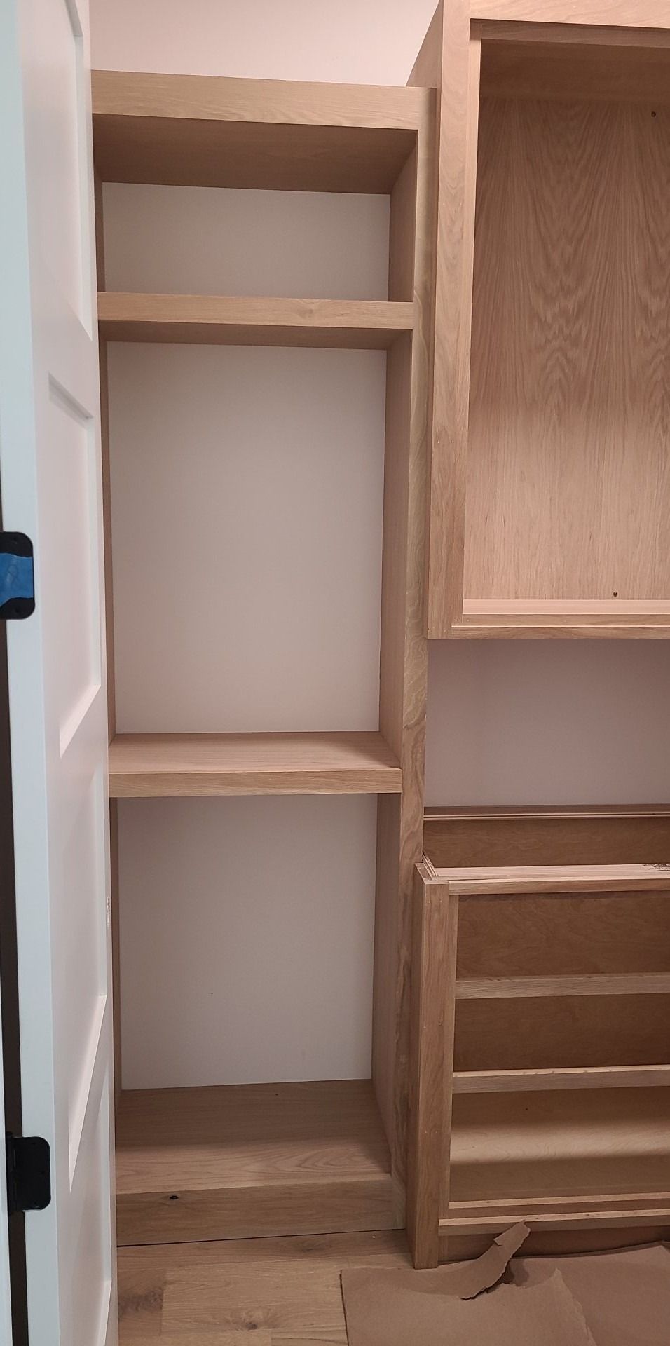 A closet is being built with wooden shelves and drawers.