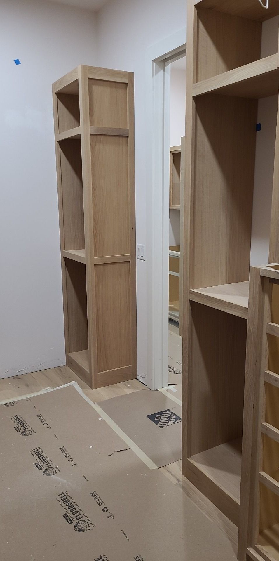 A walk in closet with wooden shelves and drawers under construction.