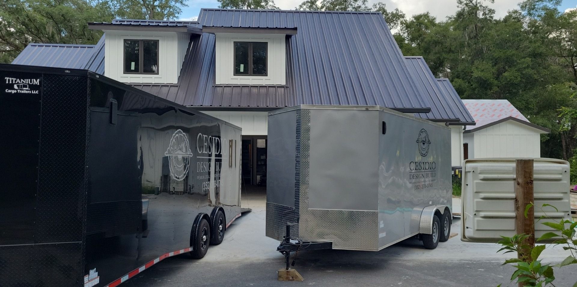 Two trailers are parked in front of a house.