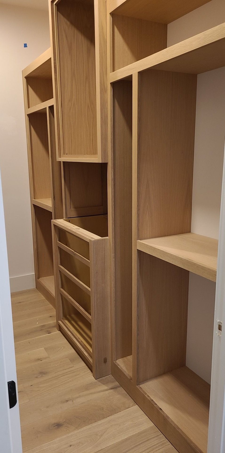 A walk in closet with wooden shelves and drawers.