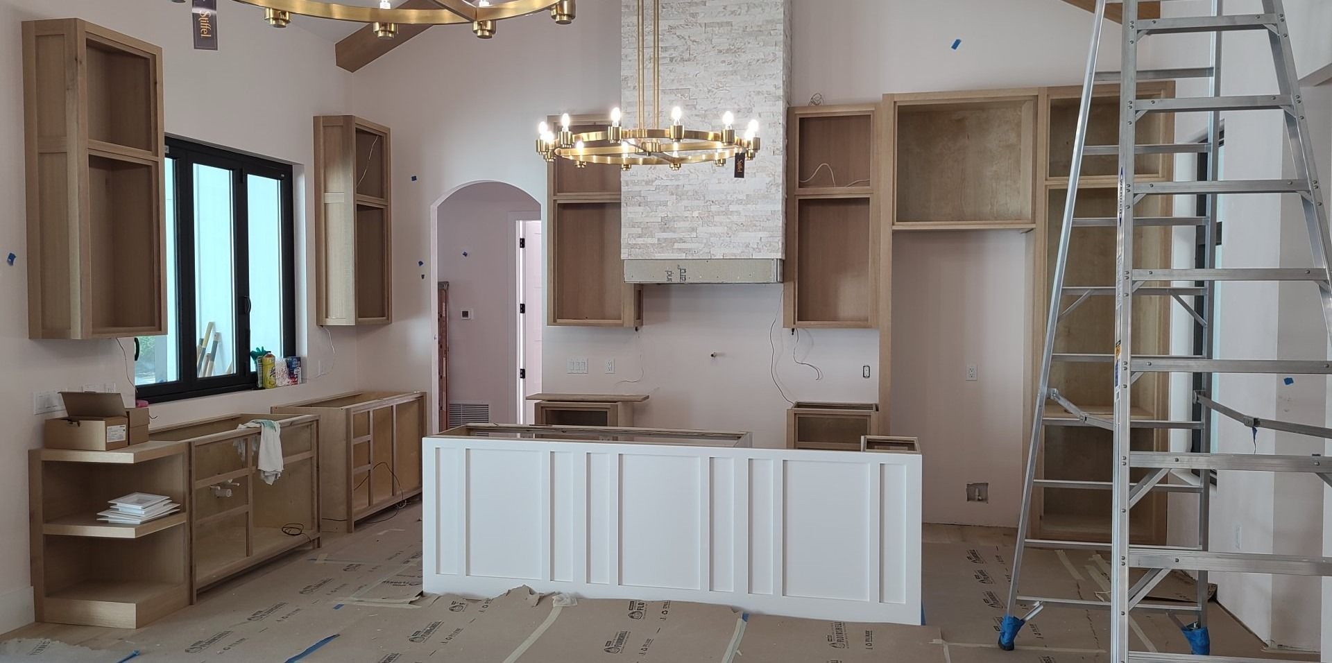 A kitchen under construction with wooden cabinets and a ladder.