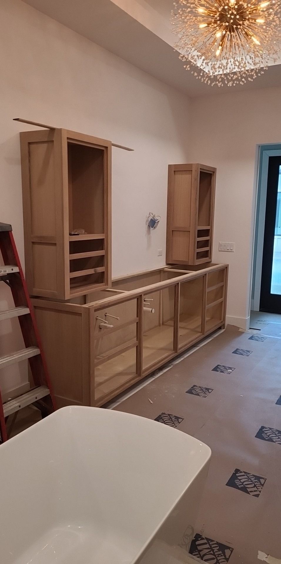 A bathroom is being remodeled with wooden cabinets and a bathtub.