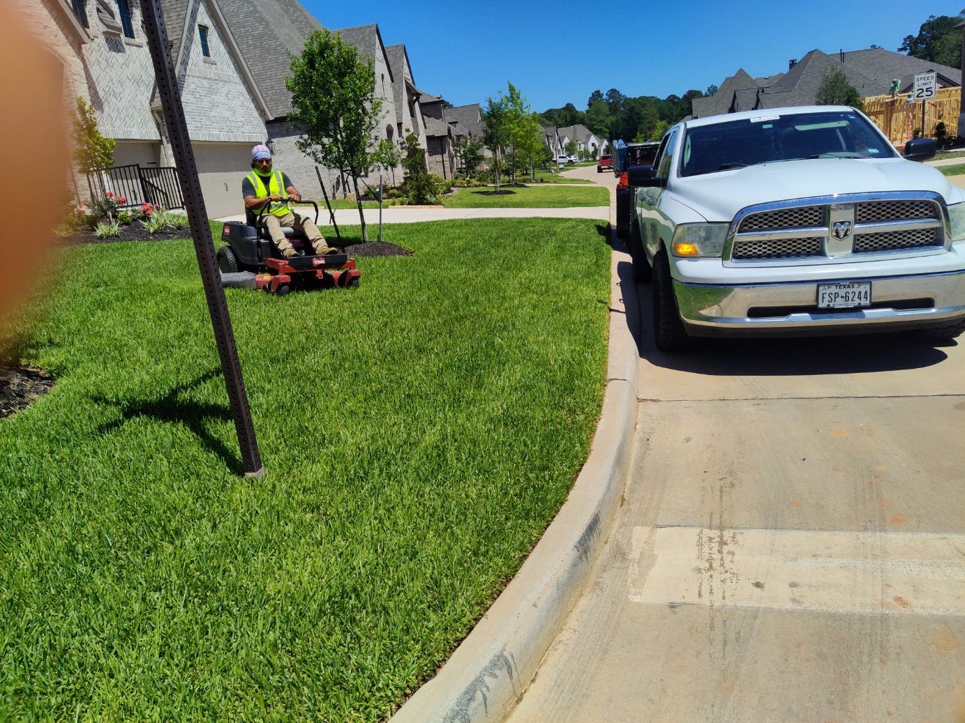 A white truck is parked on the side of the road next to a lawn mower.