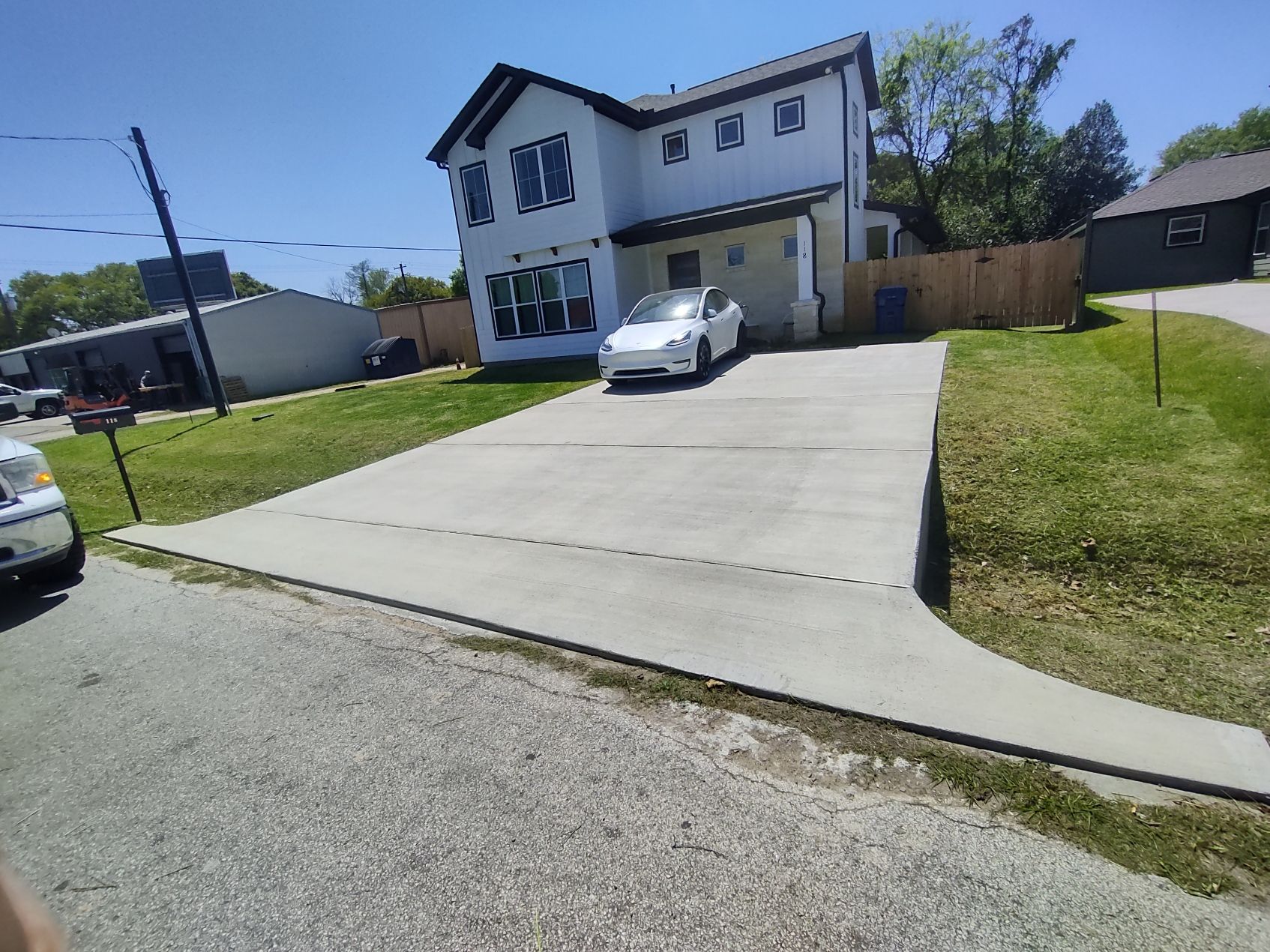 A white car is parked in a driveway in front of a house.