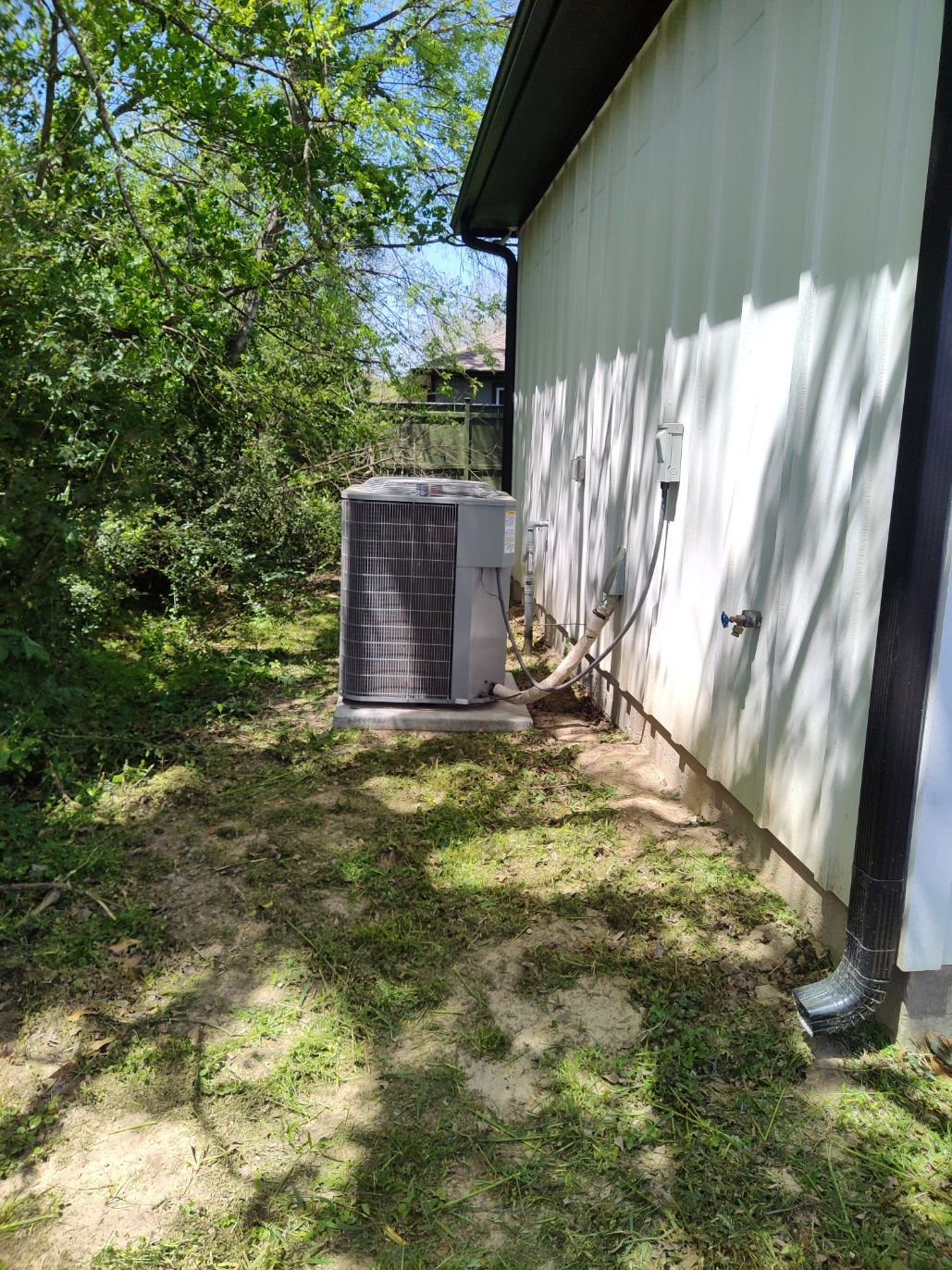 A large air conditioner is sitting on the side of a house.
