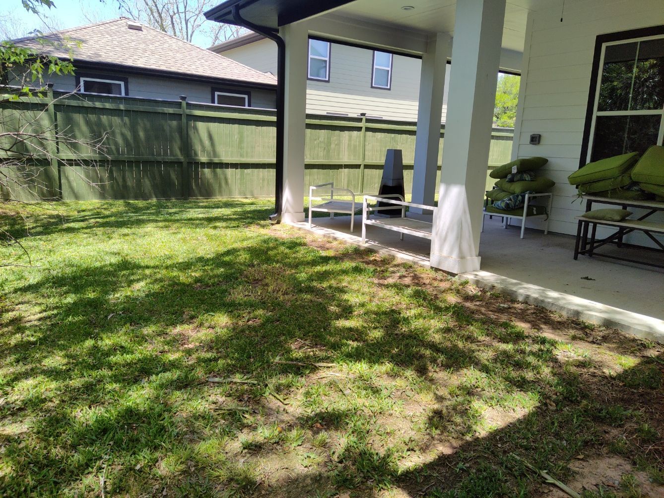 A backyard with a covered porch and a fence.