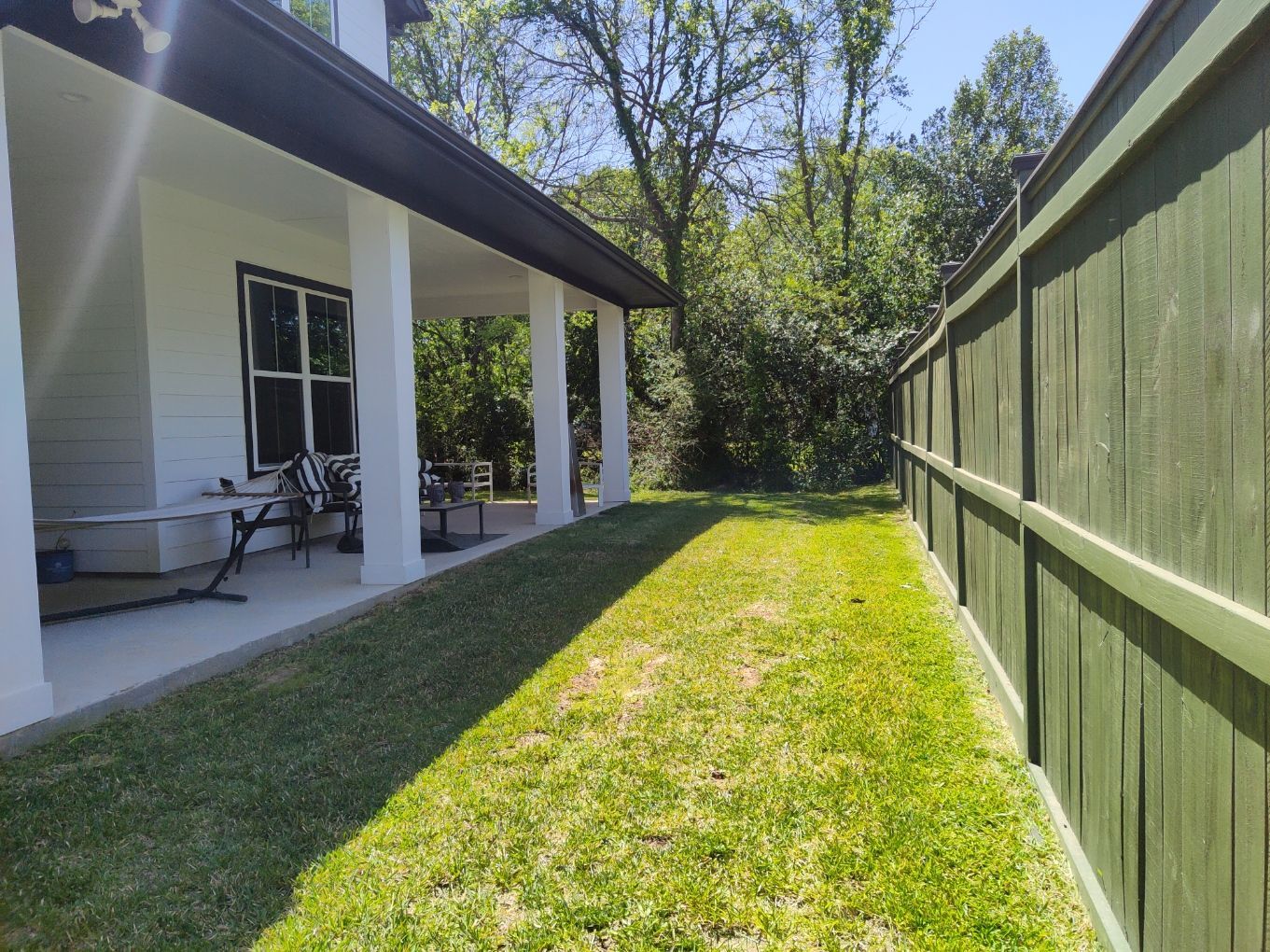 There is a green fence in the backyard of a house.