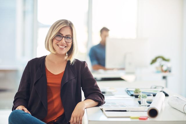 A woman is sitting at a desk in an office with her legs crossed.