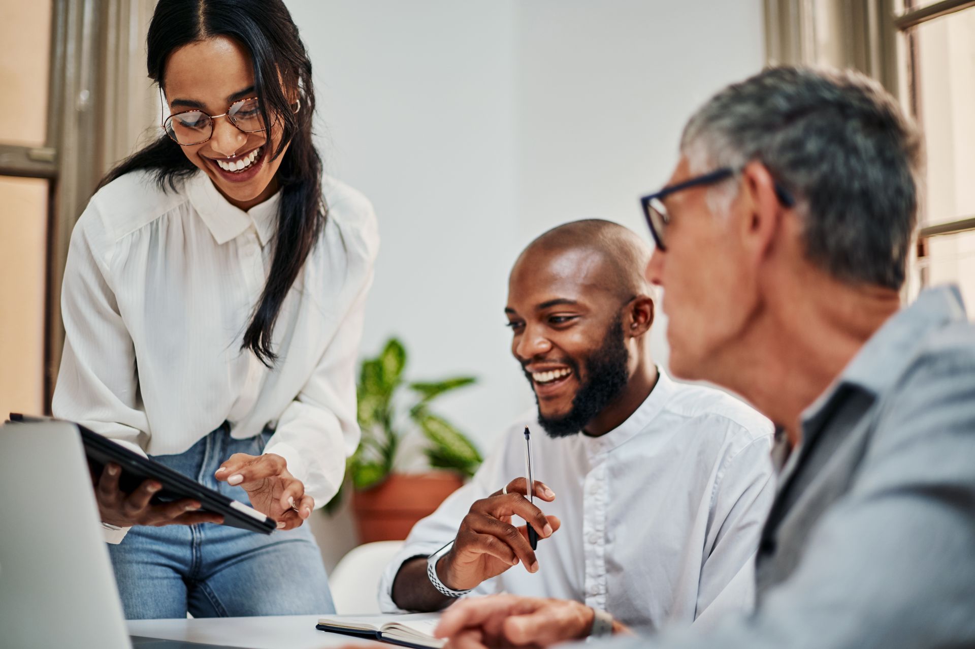 A group of people are sitting around a table looking at a tablet.