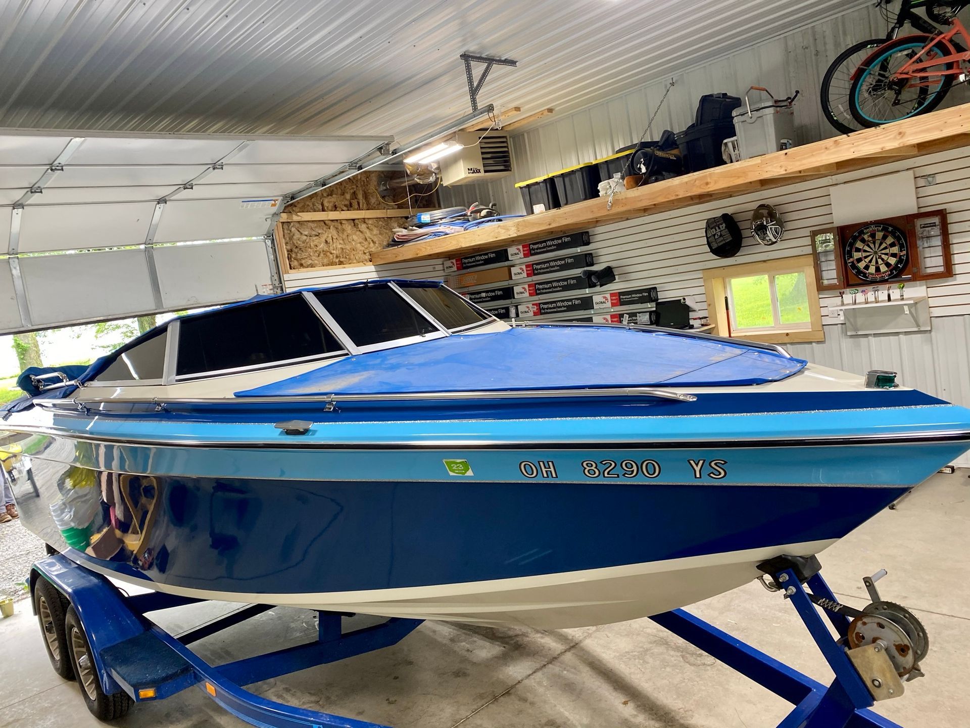 A blue and white boat is parked in a garage.