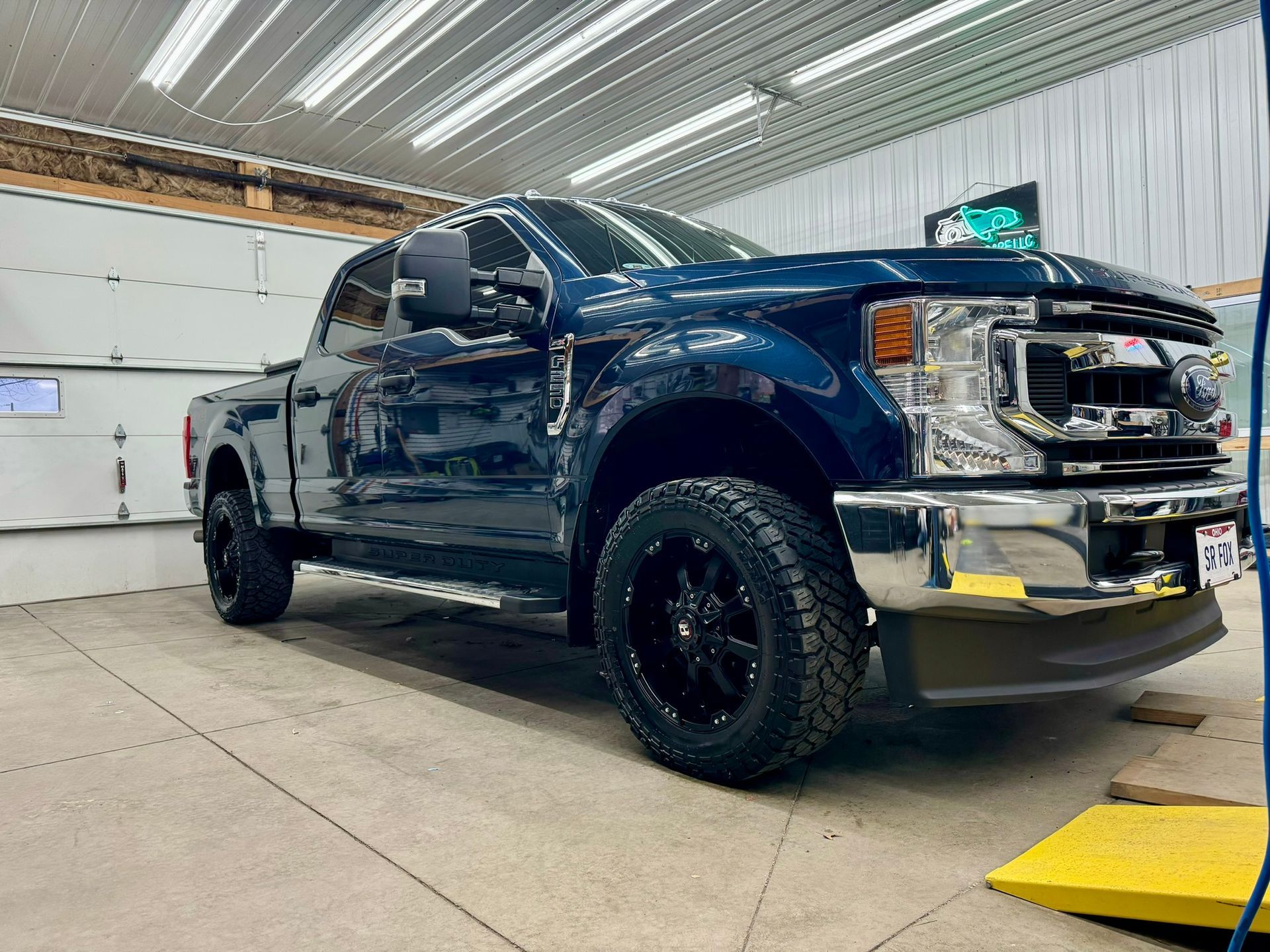 A blue ford f250 pickup truck is parked in a garage.
