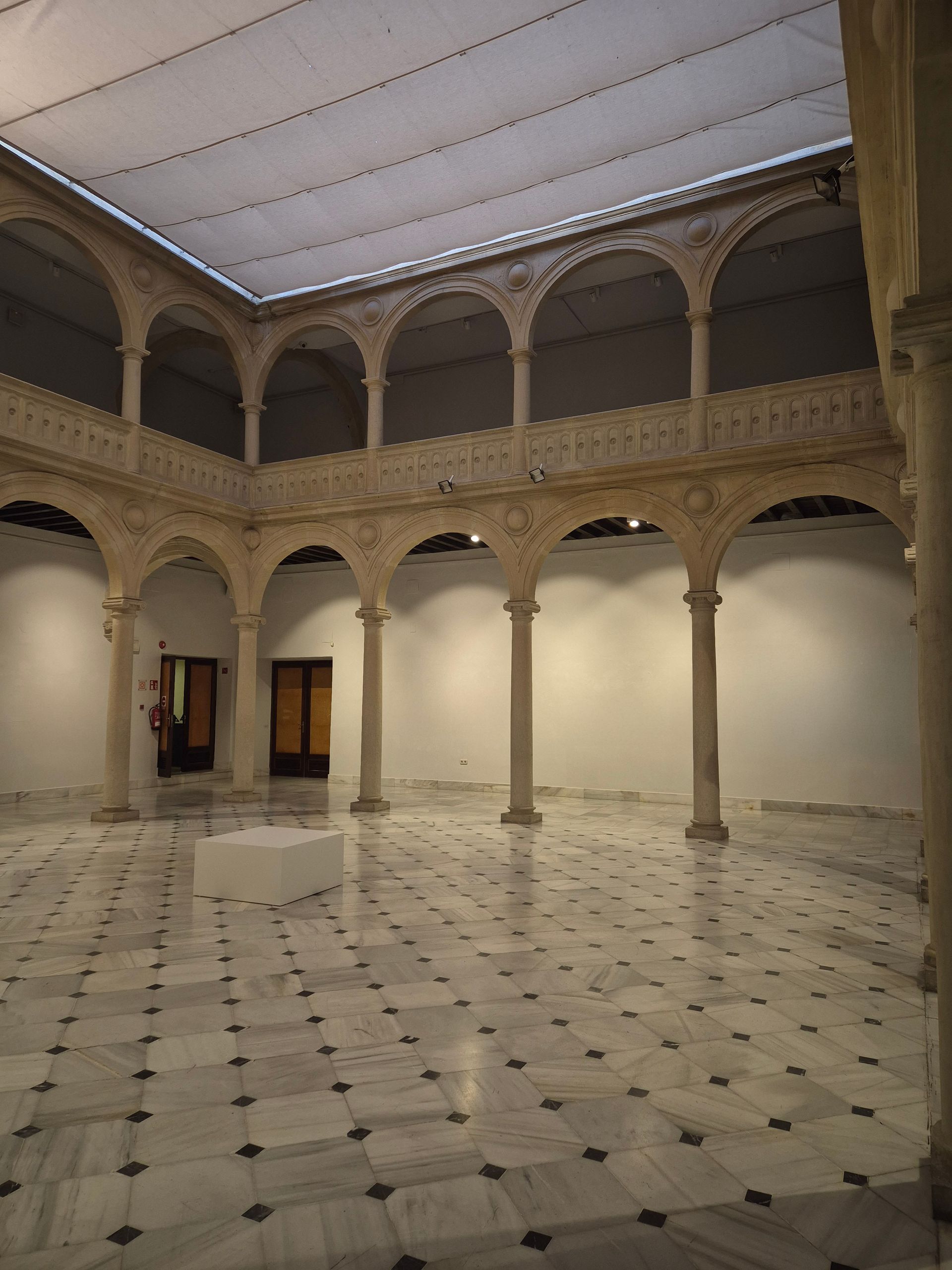 Ornate, marble-floored courtyard with arches and columns, a second-story balcony, and a skylight.