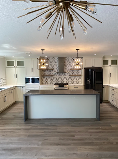 A kitchen with white cabinets and a large island in the middle.