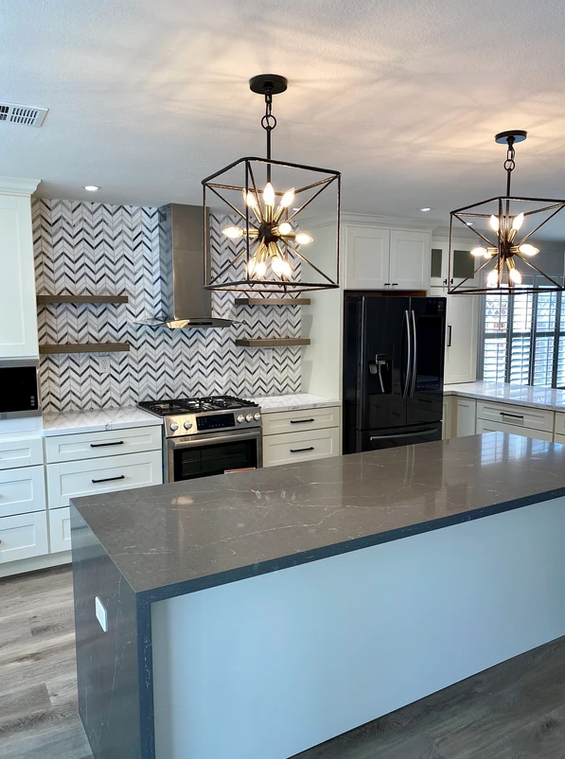 A kitchen with white cabinets , a stove , a refrigerator , and a large island.