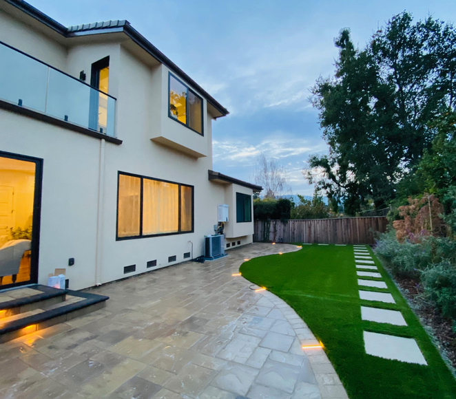 The backyard of a house with a patio and a walkway leading to it.