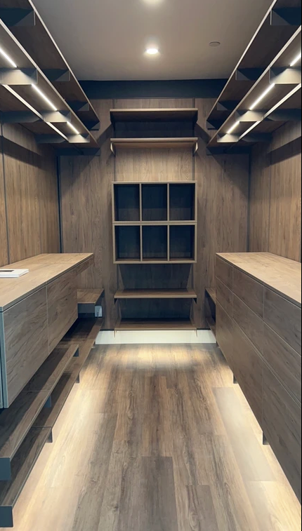 A walk in closet with wooden shelves and a wooden floor.