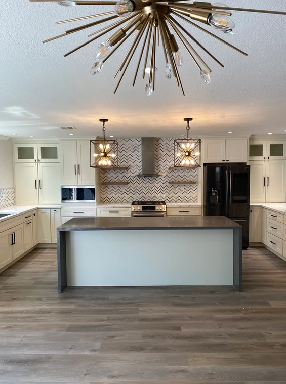 A kitchen with a large island in the middle and a chandelier hanging from the ceiling.