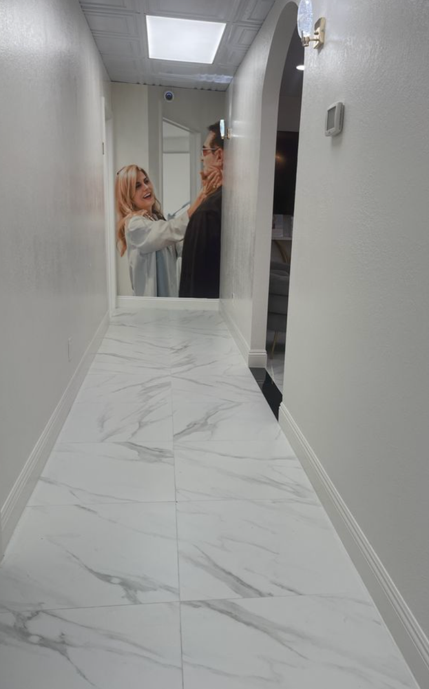 A woman is getting her hair cut in a hallway in front of a mirror.