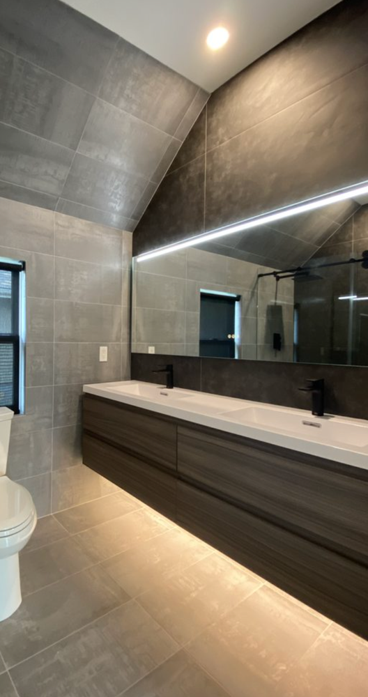 A bathroom with two sinks , a toilet and a large mirror.